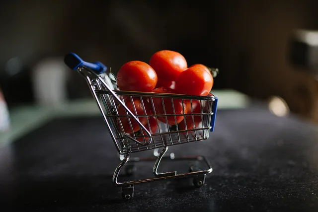 A small metallic shopping cart is filled with vibrant red tomatoes resting on a dark kitchen countertop. Soft morning light highlights the freshness of the produce. Why Ghost Kitchen Local SEO Matters Without a Storefront